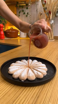 a person pouring sauce on top of a pastry