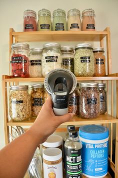 a person is holding an automatic coffee grinder in front of some jars and spices