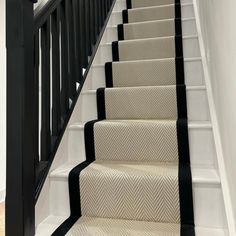 a set of stairs with black handrails and beige carpeting on the bottom