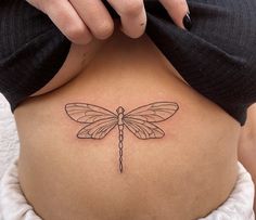 a woman's back with a tattoo design on her stomach and the dragonfly