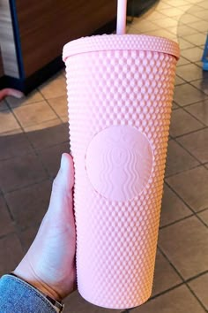 a person holding up a pink starbucks cup