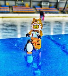 a toy tiger riding on top of a skateboard in front of an ice rink