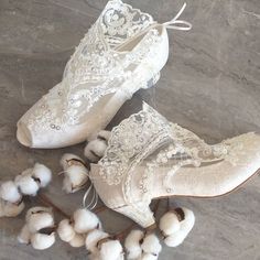 two pairs of white shoes with lace on them and cotton balls in the foreground