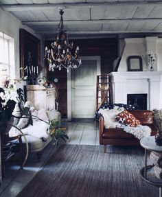 a living room filled with furniture and a chandelier hanging over the fire place