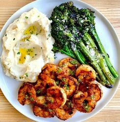 a white plate topped with shrimp, mashed potatoes and asparagus next to broccoli