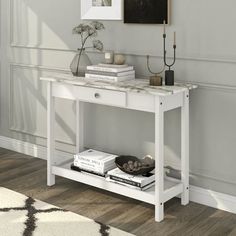 a white console table with marble top and drawers in a living room next to a wall