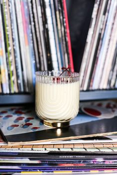 a glass filled with white liquid sitting on top of a table next to a stack of cds