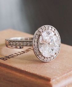 a close up of a diamond ring on top of a wooden box with the words brilliant written below it