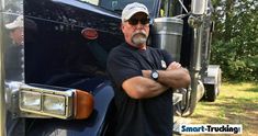 a man standing in front of a semi truck with his arms crossed and looking at the camera