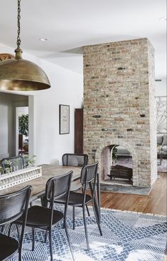 the dining room table is surrounded by black chairs and a large brick fireplace in the background