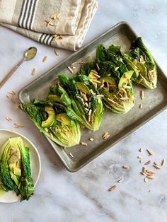 lettuce wraps with almonds and sunflower seeds on a baking sheet next to a plate