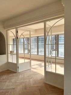 an empty room with wooden floors and large windows