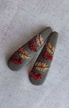 two knitted slippers with red berries and leaves on them sitting on a white surface