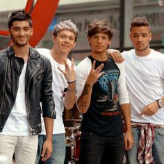 four young men posing for a photo in front of a red heart shaped object on the street