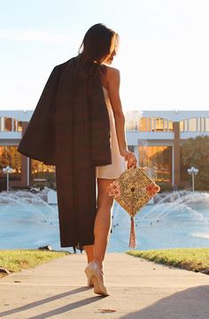 a woman walking down a sidewalk carrying a purse