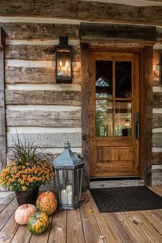 a porch with pumpkins and gourds on the wooden floor next to a lantern