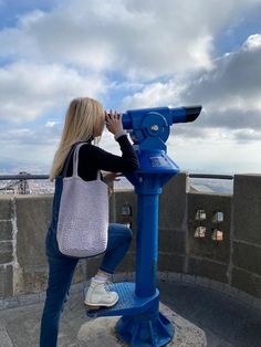 a woman looking through a telescope at the sky