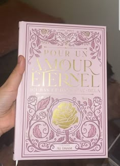 a person holding up a pink book with gold foil on it's front cover