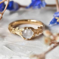 a close up of a ring on a table with blue flowers and branches in the background