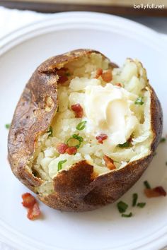 a baked potato on a white plate with bacon