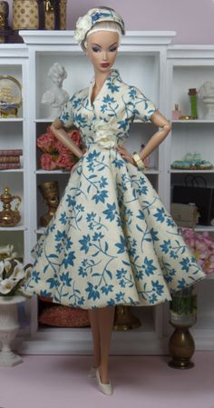 a barbie doll is standing in front of a bookcase with many items on it