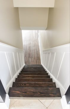 the stairs are made of wood and have white painted trim on each side, along with black handrails that lead up to the second floor