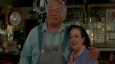 an older man and woman standing next to each other in front of a store counter