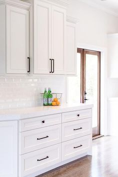 a kitchen with white cabinets and wood floors