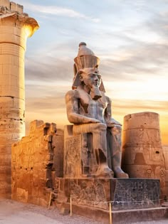 an ancient statue in front of two large stone pillars and a pillar with a light at the end