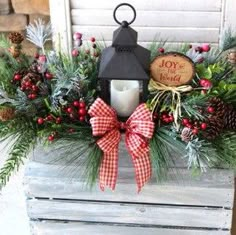 a christmas wreath with a lantern and pine cones