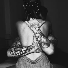 the back of a woman with tattoos on her body and hands in front of her face