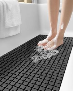 a person washing their feet in a bathtub with foam on the floor next to it