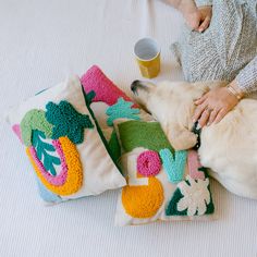 a dog is laying on the bed next to two pillows with crochet designs