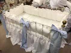 a baby crib with blue bows and white sheets on the floor next to stuffed animals