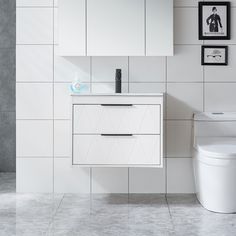 a white toilet sitting next to a bathroom sink under a mirror on a wall above it