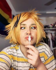 a young man with blonde hair and blue eyes is holding a toothbrush in his mouth