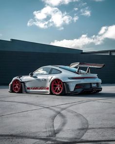 a silver sports car with red rims parked in front of a black brick building