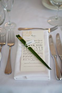 a place setting with silverware and napkins on a white table cloth, along with utensils