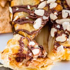 a pastry with chocolate drizzled on top and almonds scattered around it