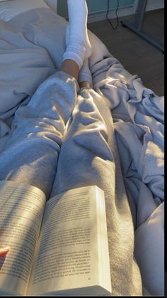 a person laying in bed with an open book on their lap and one hand resting on the pillow