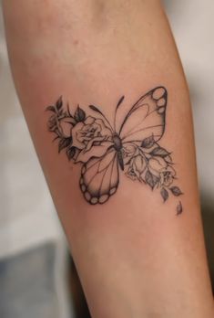 a small butterfly tattoo on the right arm and leg, with flowers around its wings