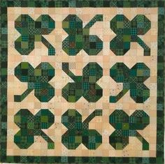 a green and white quilt with an intricate design on the front, along with two rows of squares