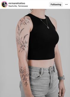 a woman with tattoos on her arm and shoulder is posing for the camera while wearing grey jeans