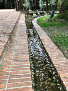 a small stream running between two brick walkways