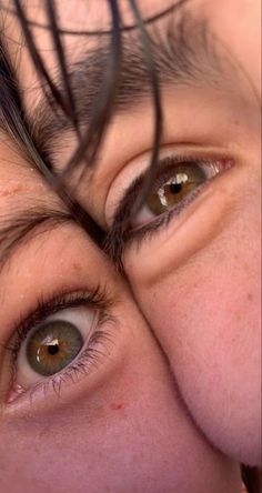 a close up of a person's eyes with long hair on top of their head