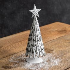 a small silver christmas tree sitting on top of a wooden table