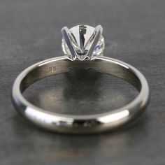 a close up view of a diamond ring on a black surface with the center stone visible