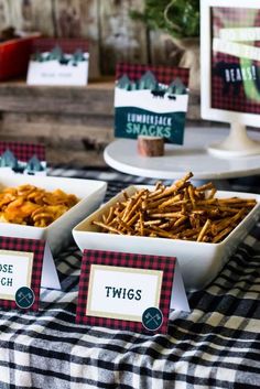 there are three trays of food on the table with place cards in front of them