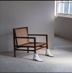 a wooden chair with white boots sitting on it's legs in front of a window