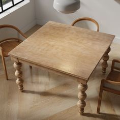 a wooden table with chairs around it in front of a window and a lamp hanging from the ceiling